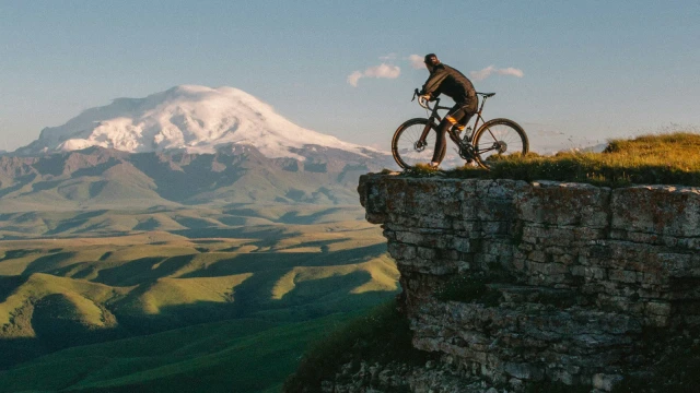 Ciclista de montaña frente a una cordillera, fotografía ambiental de la guía de MTB